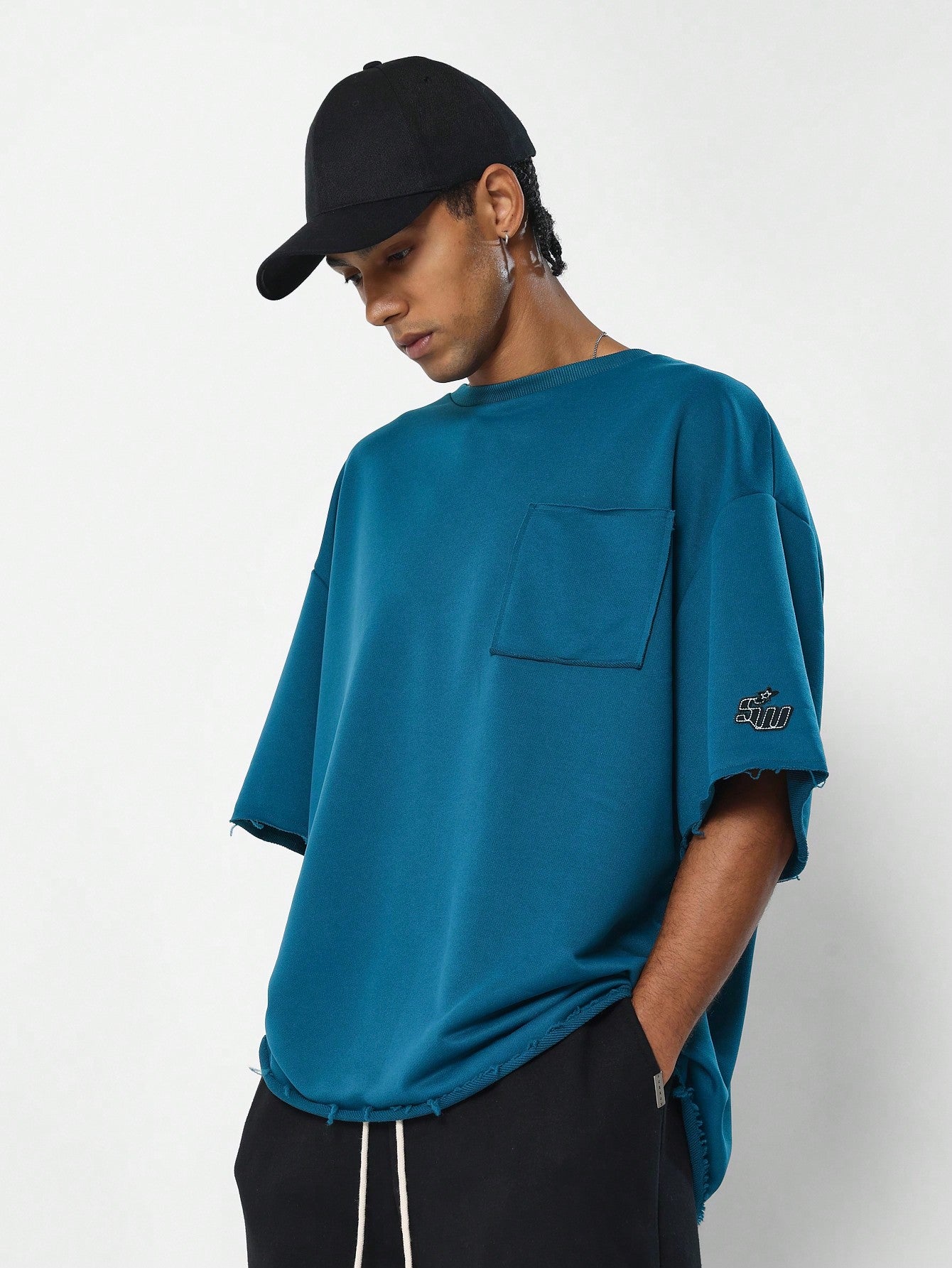 Oversized Fit Raw Edge Tee With Front Pocket And Sleeve Applique