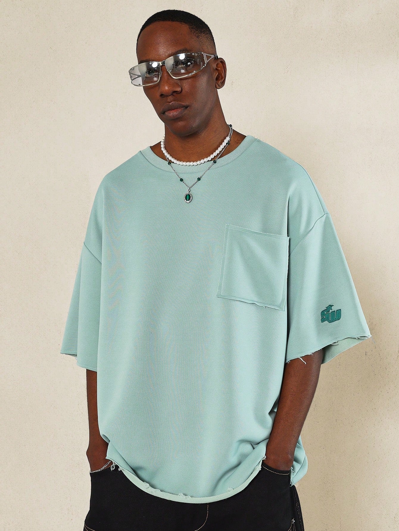 Oversized Fit Raw Edge Tee With Front Pocket And Sleeve Applique