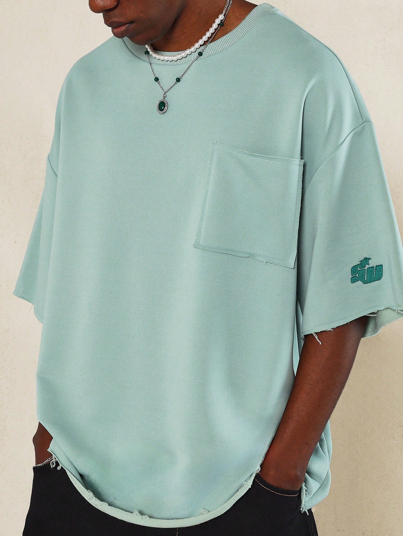 Oversized Fit Raw Edge Tee With Front Pocket And Sleeve Applique