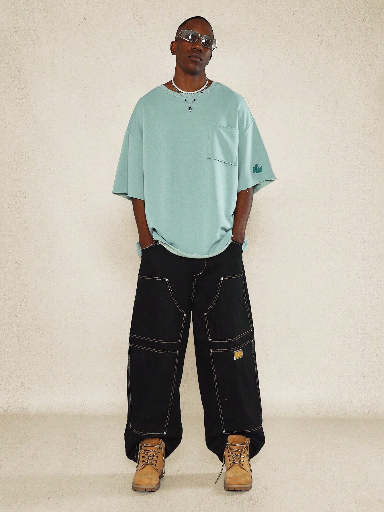 Oversized Fit Raw Edge Tee With Front Pocket And Sleeve Applique