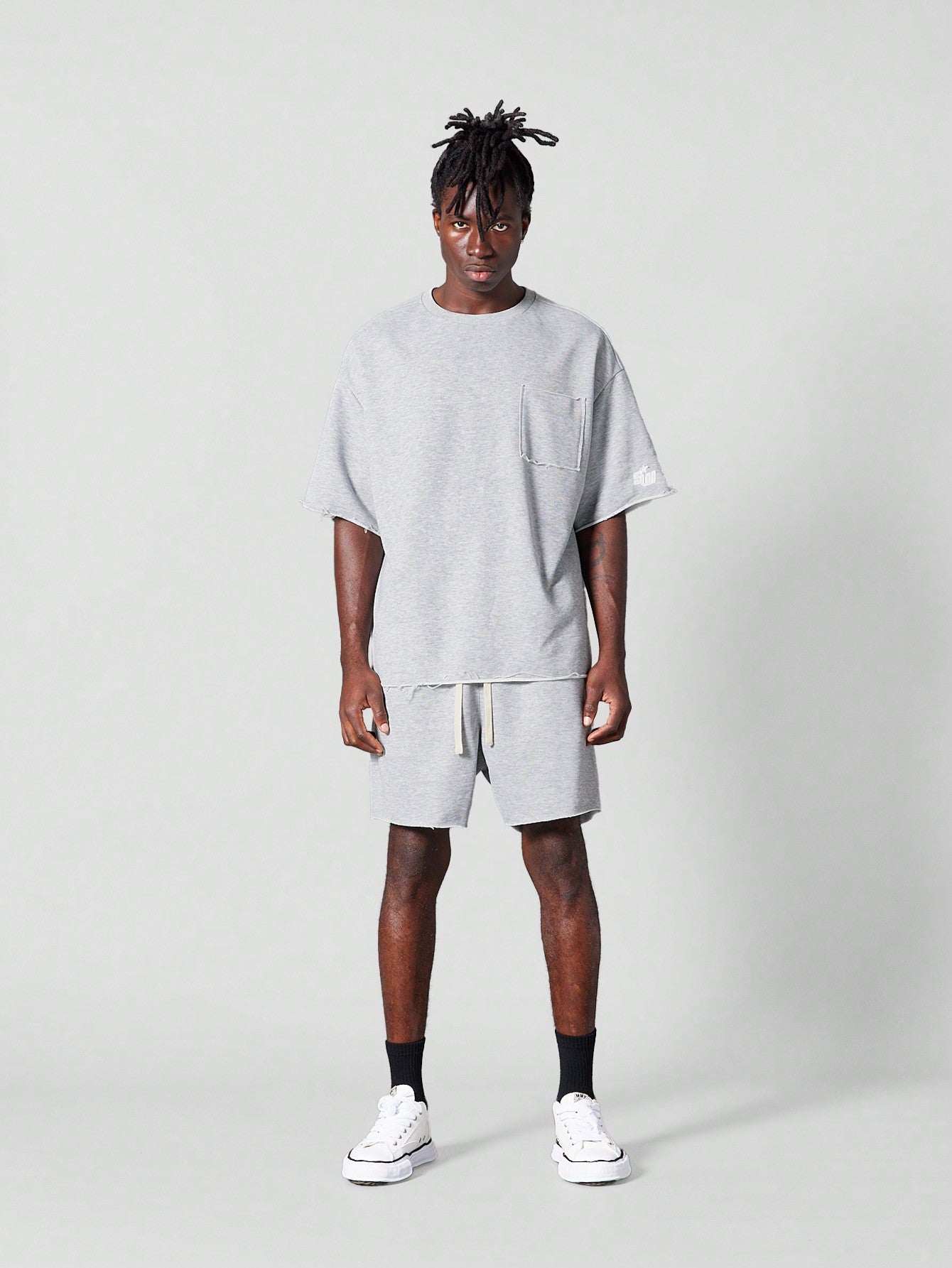 Oversized Fit Raw Edge Tee With Front Pocket And Sleeve Applique