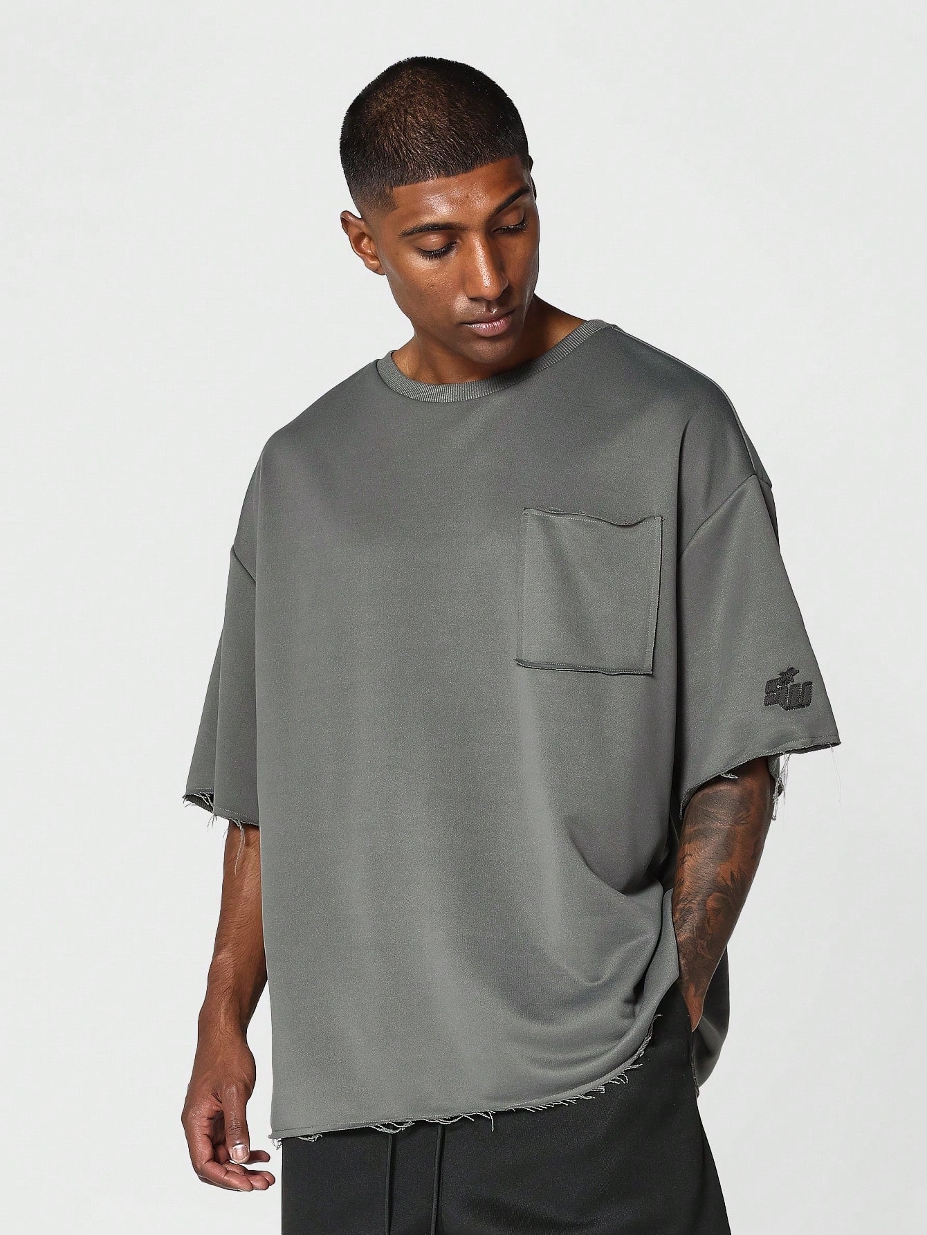 Oversized Fit Raw Edge Tee With Front Pocket And Sleeve Applique