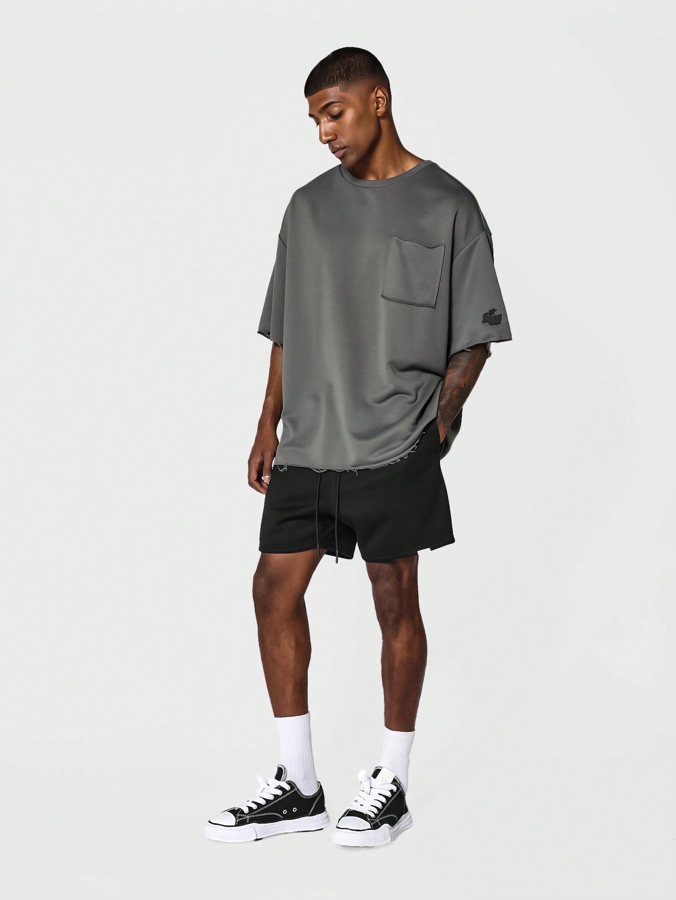 Oversized Fit Raw Edge Tee With Front Pocket And Sleeve Applique