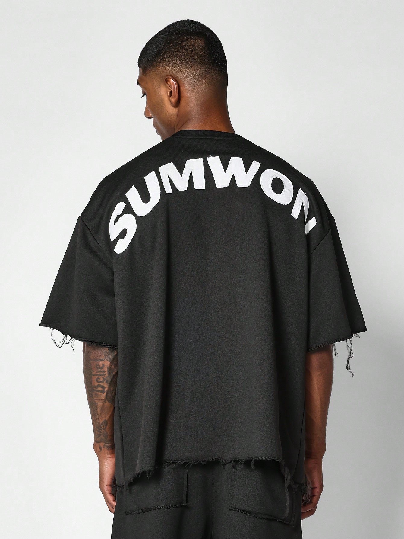 Oversized Fit Raw Edge Tee With Front Pocket And Sleeve Applique