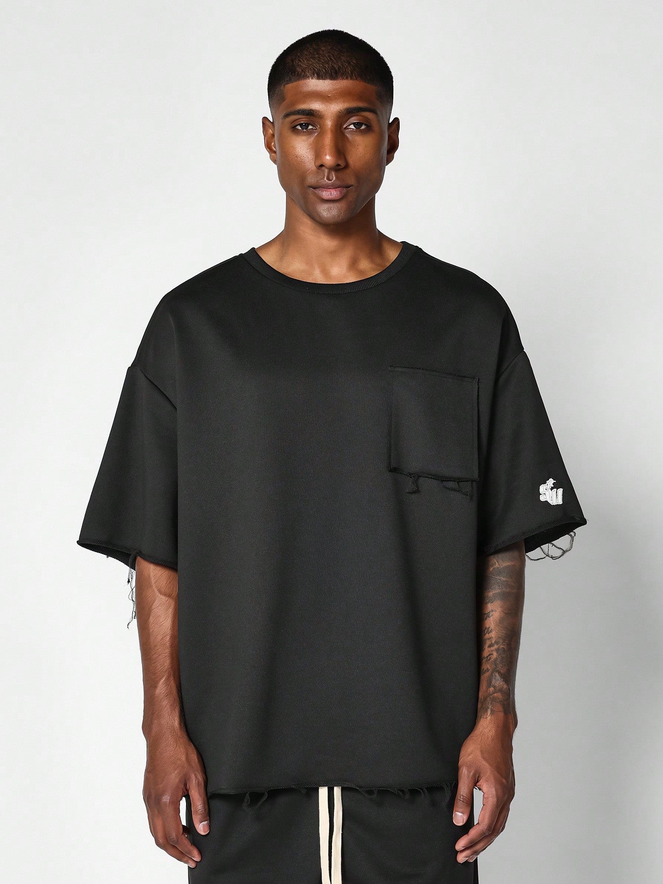 Oversized Fit Raw Edge Tee With Front Pocket And Sleeve Applique